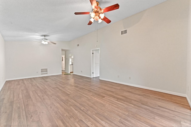 unfurnished living room with a textured ceiling, light hardwood / wood-style flooring, and lofted ceiling