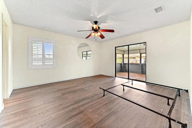 interior space with ceiling fan, wood-type flooring, and a textured ceiling