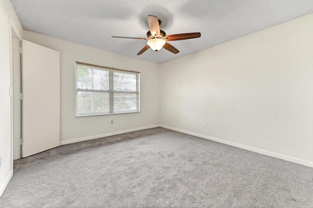 carpeted spare room featuring ceiling fan and a textured ceiling