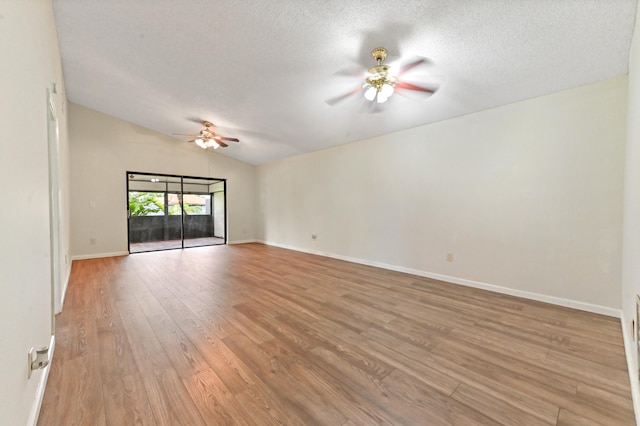 empty room featuring a textured ceiling, light hardwood / wood-style flooring, vaulted ceiling, and ceiling fan