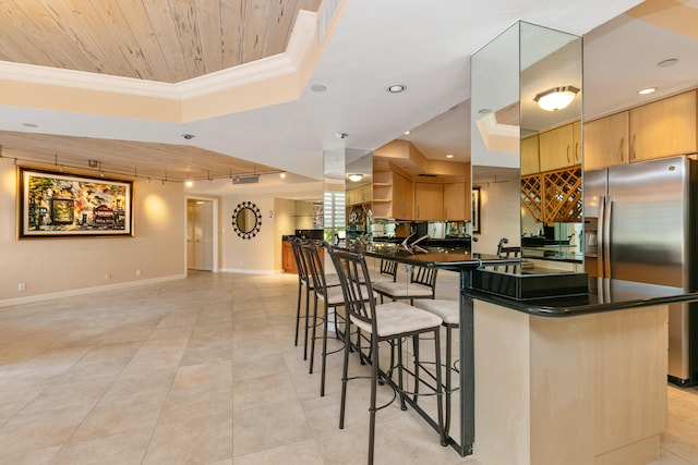 kitchen featuring stainless steel fridge, rail lighting, a kitchen breakfast bar, a raised ceiling, and crown molding