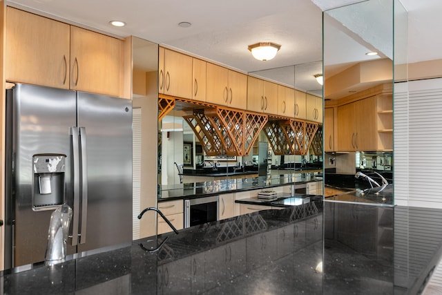 kitchen featuring kitchen peninsula, stainless steel fridge, beverage cooler, and dark stone counters