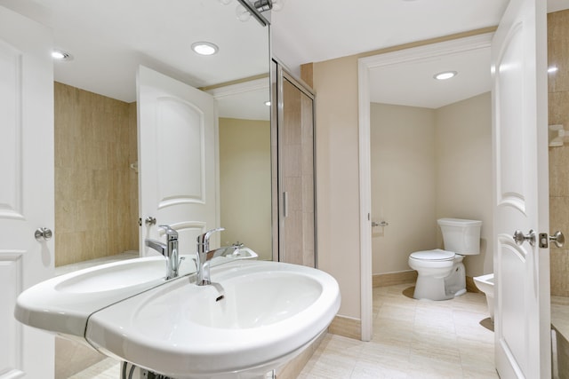 bathroom with toilet, walk in shower, sink, and tile patterned flooring