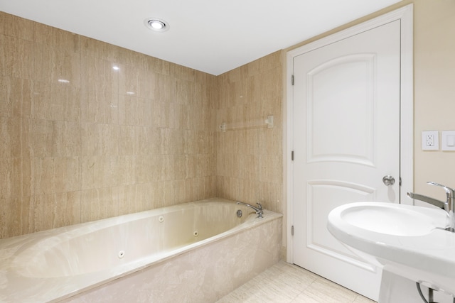 bathroom featuring a relaxing tiled tub, sink, and tile patterned flooring