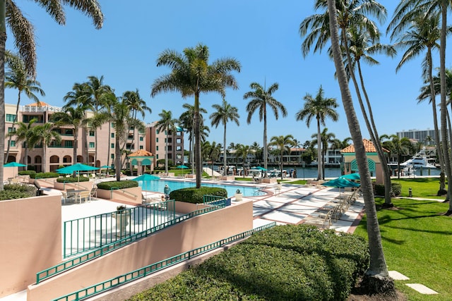 view of swimming pool featuring a water view, a patio, and a lawn