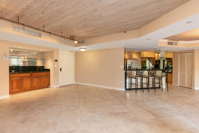 unfurnished living room with wood ceiling, a tray ceiling, rail lighting, light tile patterned floors, and a chandelier