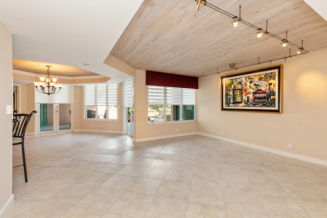 unfurnished living room with wood ceiling, a raised ceiling, rail lighting, a chandelier, and light tile patterned flooring