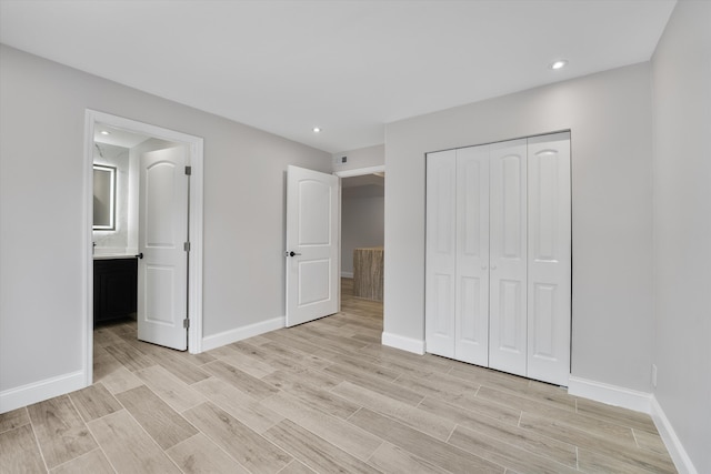 unfurnished bedroom featuring light hardwood / wood-style flooring, a closet, and ensuite bath