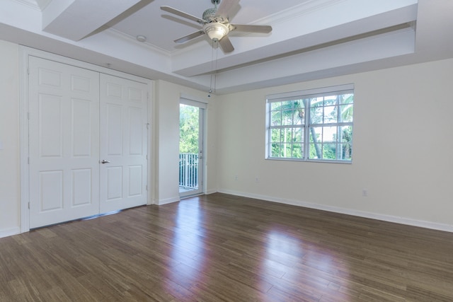 unfurnished bedroom featuring dark hardwood / wood-style flooring, a tray ceiling, and ceiling fan