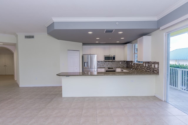 kitchen featuring white cabinets, kitchen peninsula, appliances with stainless steel finishes, and dark stone counters