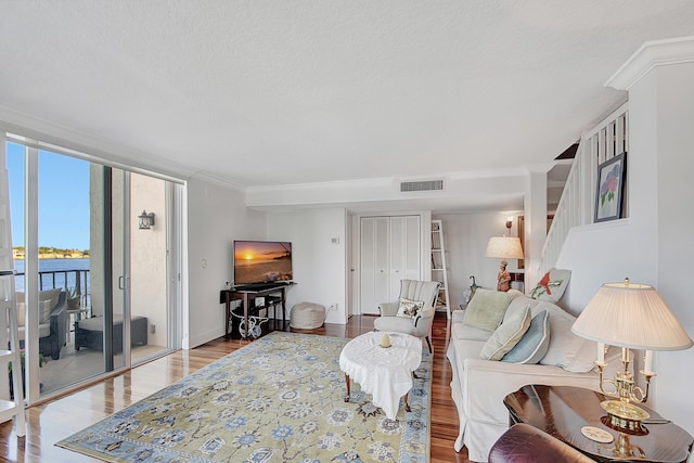 living room with a textured ceiling, light hardwood / wood-style flooring, and a water view