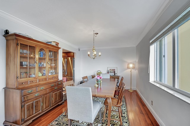 dining area featuring an inviting chandelier, crown molding, and dark hardwood / wood-style flooring