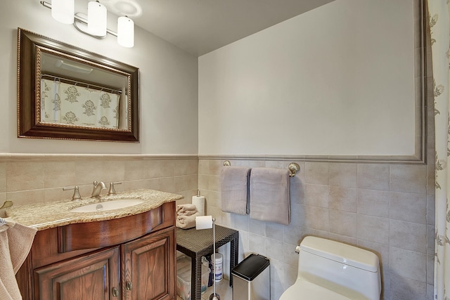 bathroom featuring vanity, tile walls, and toilet