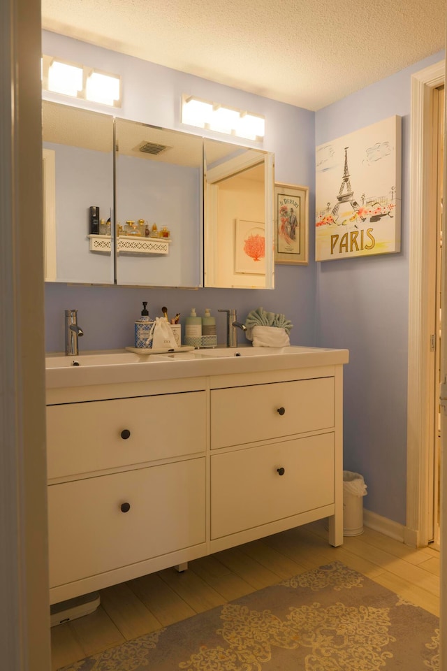 bathroom with hardwood / wood-style floors, vanity, and a textured ceiling