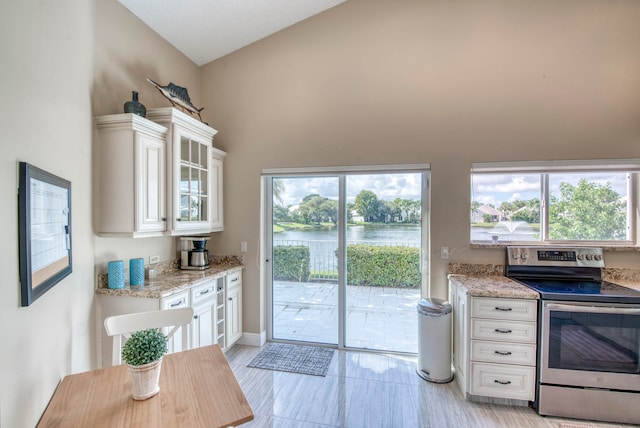 kitchen with plenty of natural light, white cabinetry, electric range, and a water view