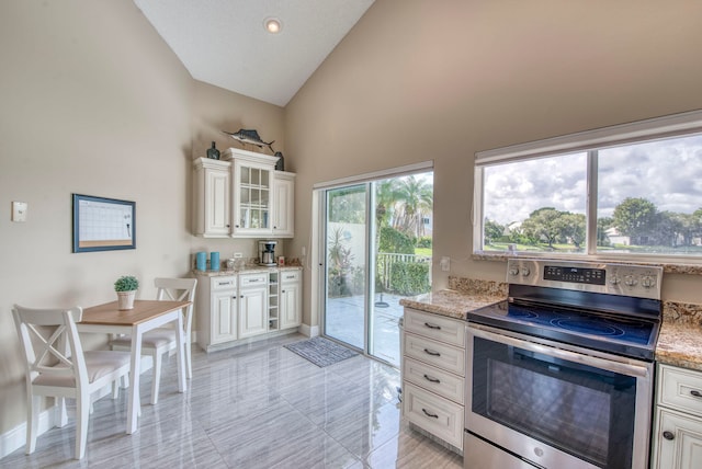 kitchen featuring light stone countertops, white cabinetry, stainless steel range with electric stovetop, and high vaulted ceiling