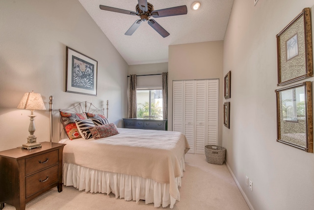 bedroom featuring a textured ceiling, a closet, ceiling fan, vaulted ceiling, and light colored carpet