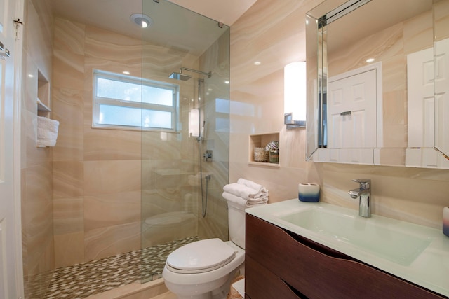 bathroom featuring tile walls, vanity, toilet, and walk in shower