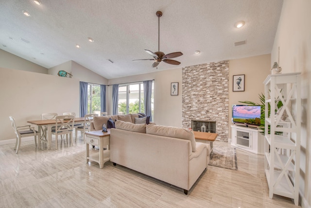 living room featuring ceiling fan, a stone fireplace, a textured ceiling, and lofted ceiling