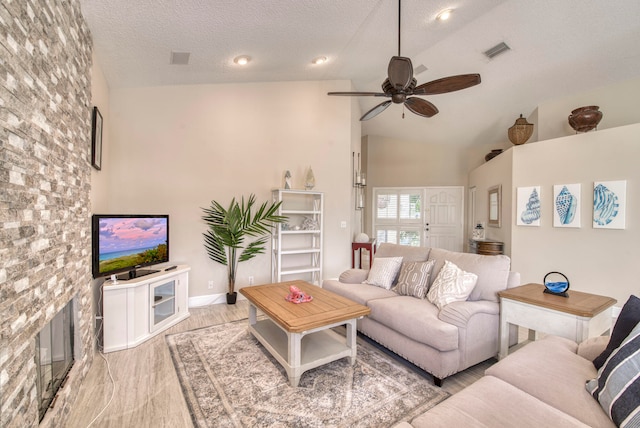 living room featuring light hardwood / wood-style flooring, a textured ceiling, high vaulted ceiling, and ceiling fan