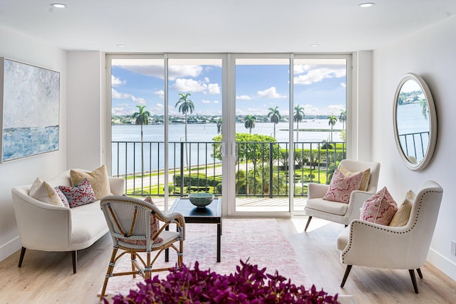 living area with plenty of natural light, a water view, and light wood-type flooring