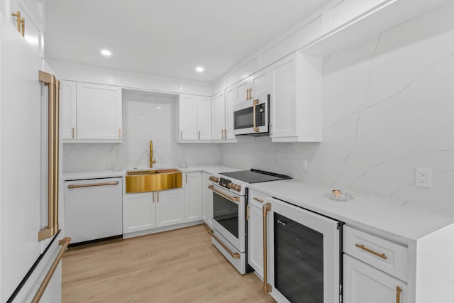 kitchen with white appliances, white cabinets, sink, wine cooler, and light hardwood / wood-style flooring