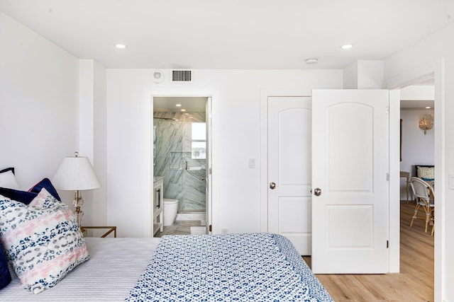 bedroom featuring connected bathroom and light hardwood / wood-style floors