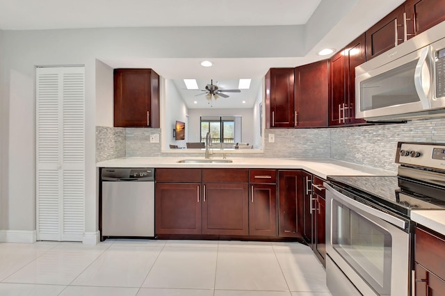 kitchen with decorative backsplash, sink, light tile patterned floors, appliances with stainless steel finishes, and a skylight