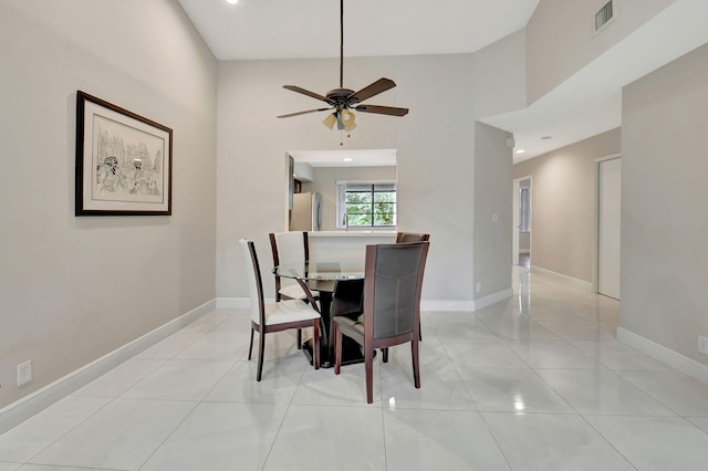 dining space with light tile patterned floors, a high ceiling, and ceiling fan