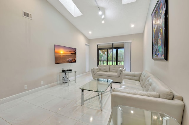 living room featuring high vaulted ceiling, light tile patterned flooring, a textured ceiling, and a skylight