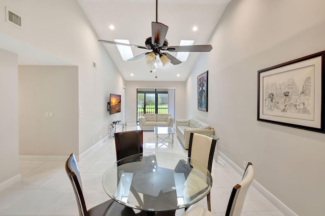 dining space featuring ceiling fan, high vaulted ceiling, a skylight, and light tile patterned floors