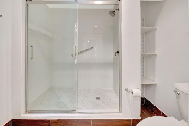 bathroom with toilet, hardwood / wood-style floors, and a shower with door