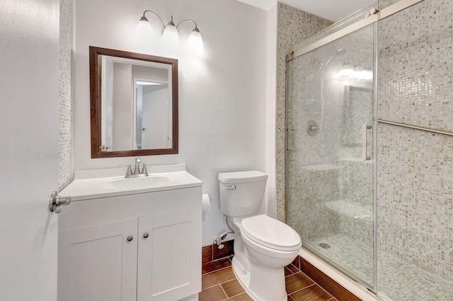 bathroom featuring toilet, hardwood / wood-style floors, a shower with shower door, and vanity