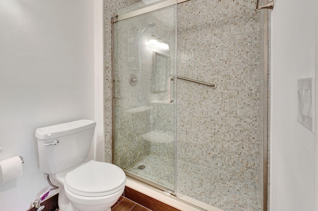 bathroom with toilet, hardwood / wood-style flooring, and an enclosed shower