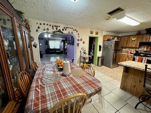 tiled dining space featuring ceiling fan and a textured ceiling