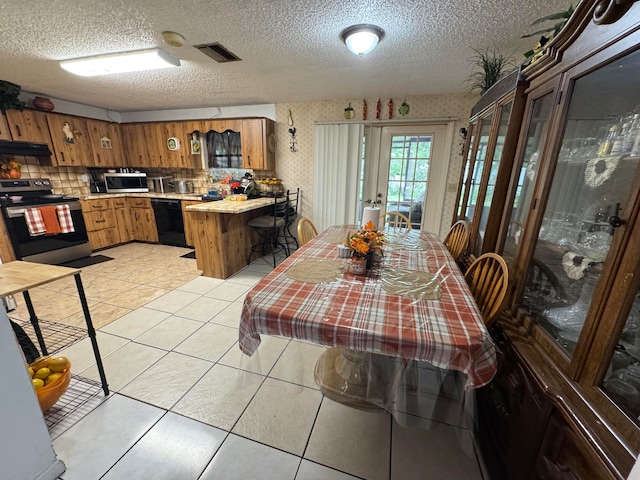 tiled dining space with french doors and a textured ceiling