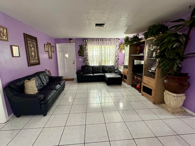 living room with a textured ceiling and light tile patterned flooring