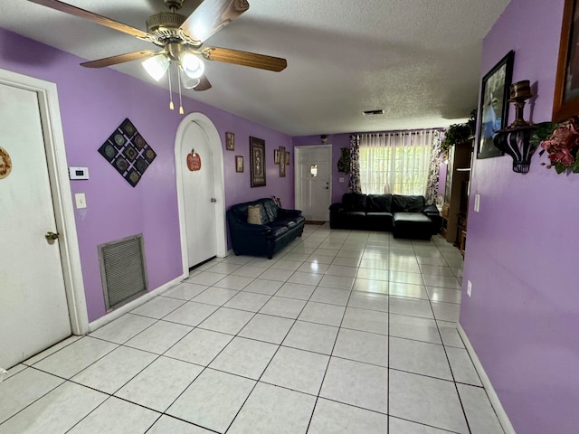 unfurnished living room featuring a textured ceiling, light tile patterned floors, and ceiling fan