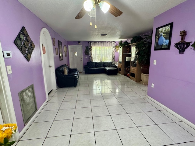 living room with ceiling fan, a textured ceiling, and light tile patterned flooring