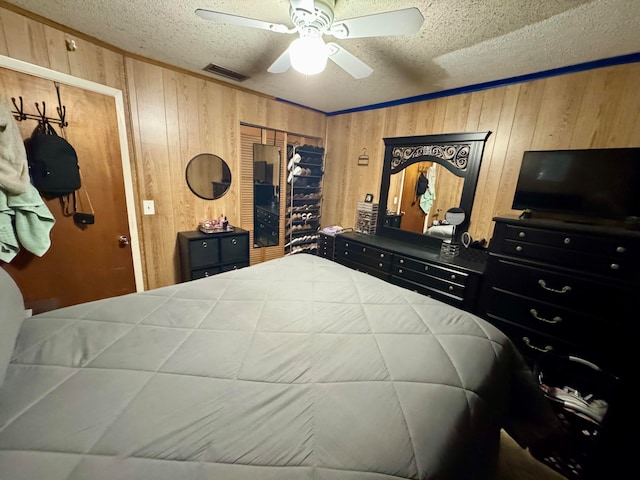 bedroom featuring ceiling fan, a textured ceiling, and wood walls