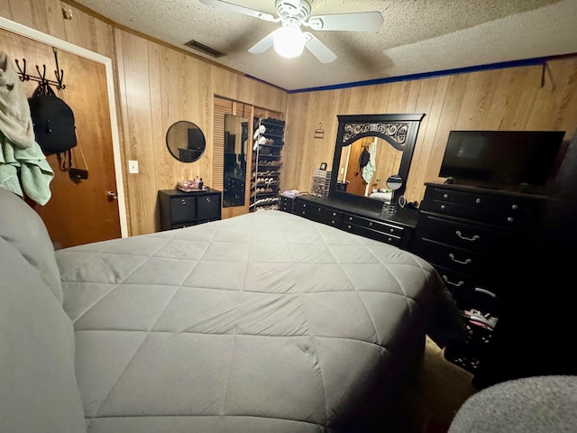 bedroom with wooden walls, a textured ceiling, and ceiling fan