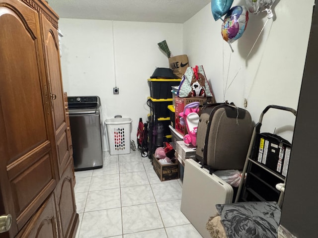 clothes washing area featuring washer / dryer, a textured ceiling, and light tile patterned floors