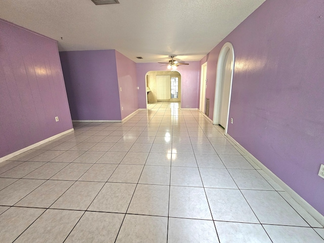 275 SE 16th Ave, Okeechobee, FL 34974 - empty room with arched walkways, a ceiling fan, a textured ceiling, light tile patterned flooring, and baseboards