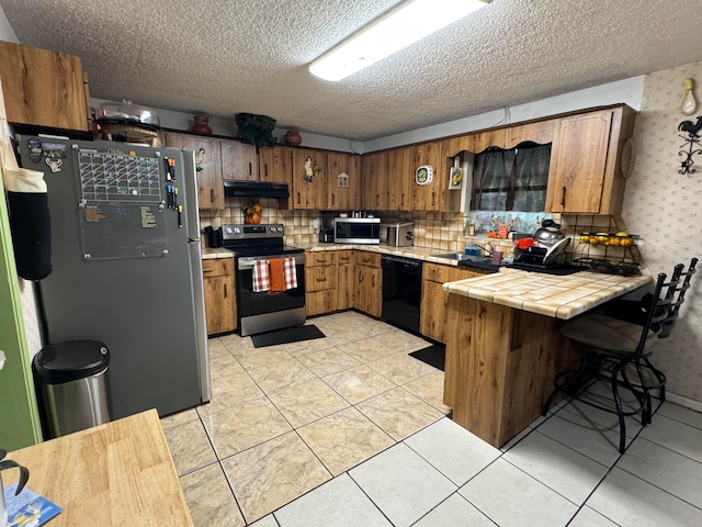 kitchen with tile countertops, appliances with stainless steel finishes, kitchen peninsula, and light tile patterned floors