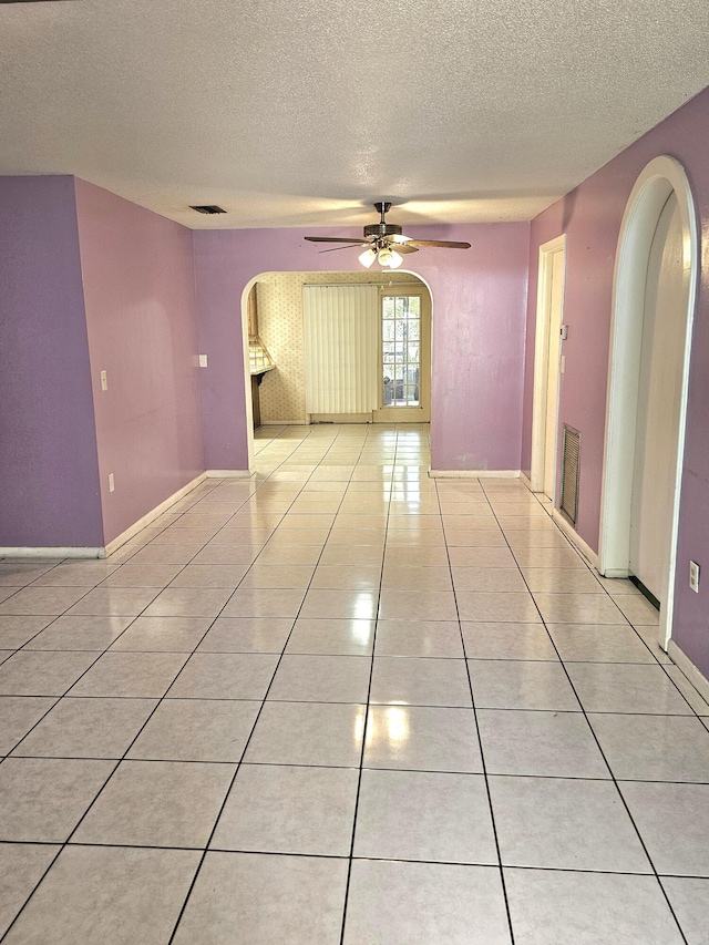 275 SE 16th Ave, Okeechobee, FL 34974 - empty room with arched walkways, a textured ceiling, ceiling fan, light tile patterned floors, and baseboards