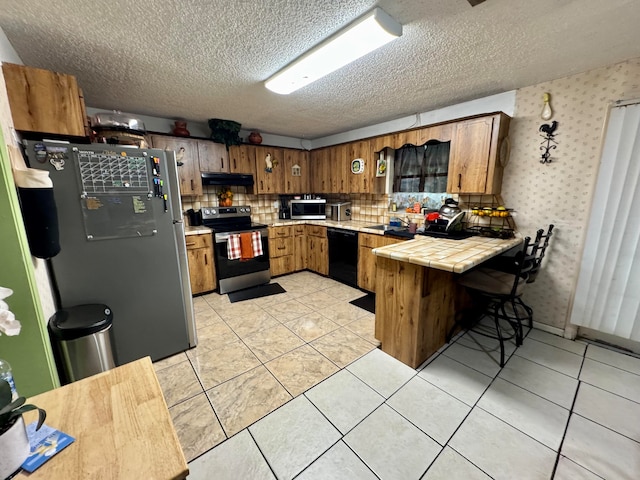 kitchen featuring tasteful backsplash, appliances with stainless steel finishes, light tile patterned flooring, kitchen peninsula, and tile counters