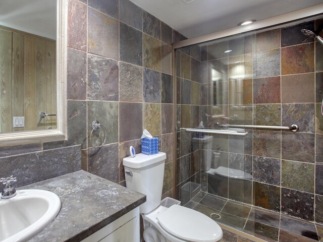 bathroom featuring tile walls, vanity, an enclosed shower, and toilet