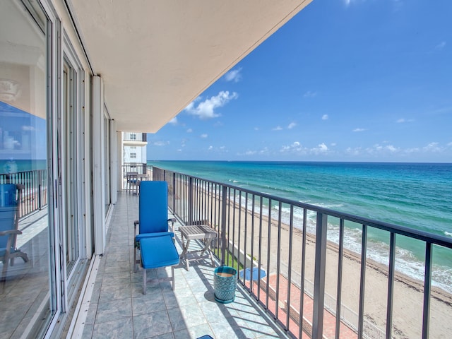 balcony with a water view and a view of the beach