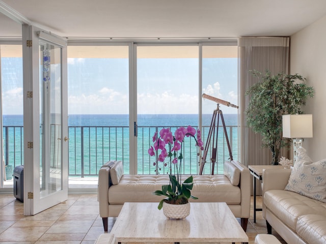 tiled living room featuring floor to ceiling windows and a water view