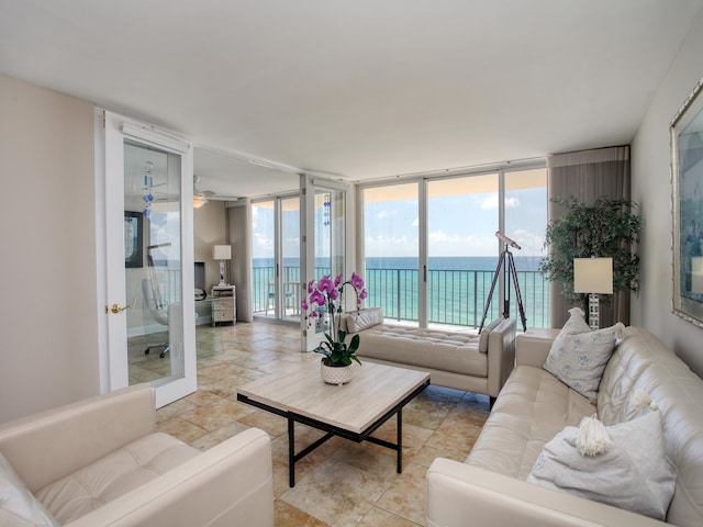 living room featuring ceiling fan, expansive windows, and a water view